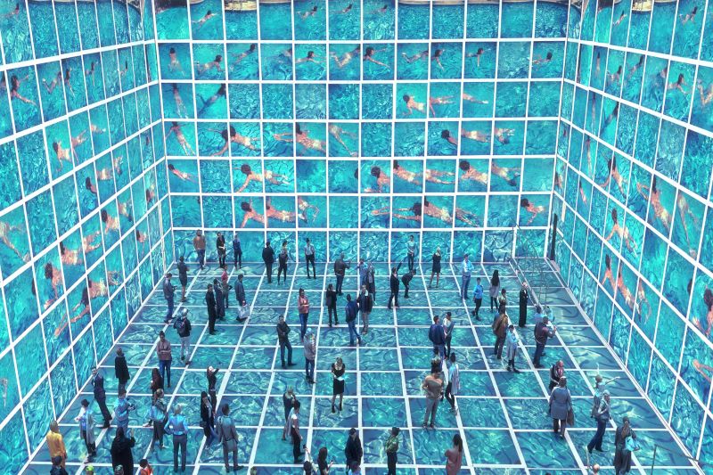 A room full of videos of David Hockneys Art: swimming figures in a bright blue pool. The videos cover the whole room, ceiling and floor.