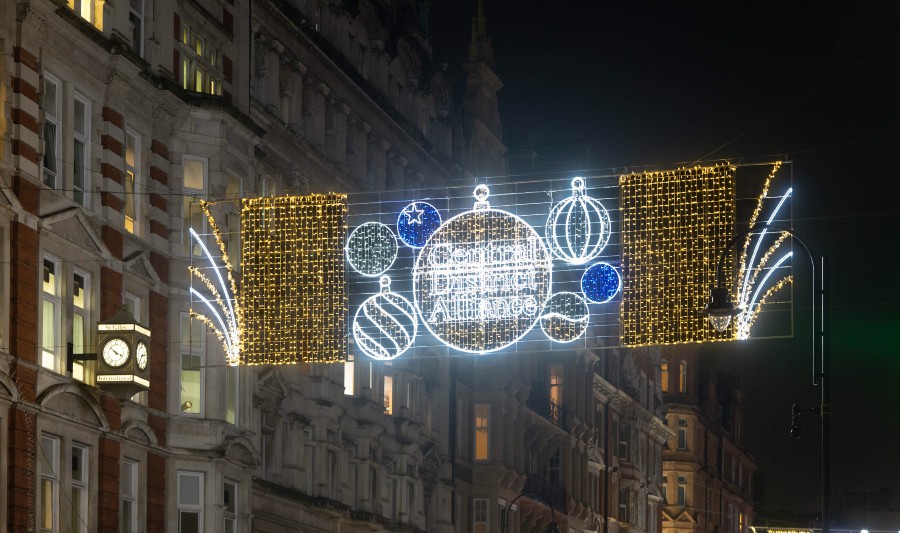 Christmas Lights on a high street, the lights are in the shape of a bauble in blue, gold and red 