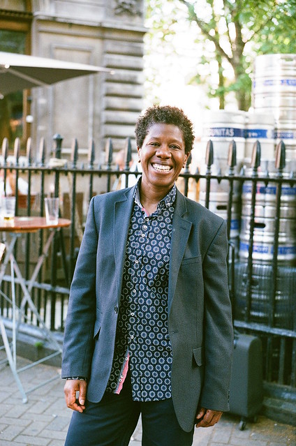 Woman standing smiling outdoors wearing a shirt and blazer